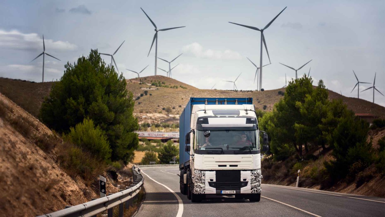 Um camião de teste na estrada em Espanha com turbinas eólicas ao fundo
